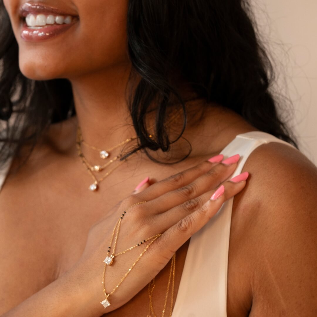 Woman smiling while wearing multiple Modern Mangal mangalsutras with various gold chains and sparkling pendants, highlighting the versatile and elegant design.