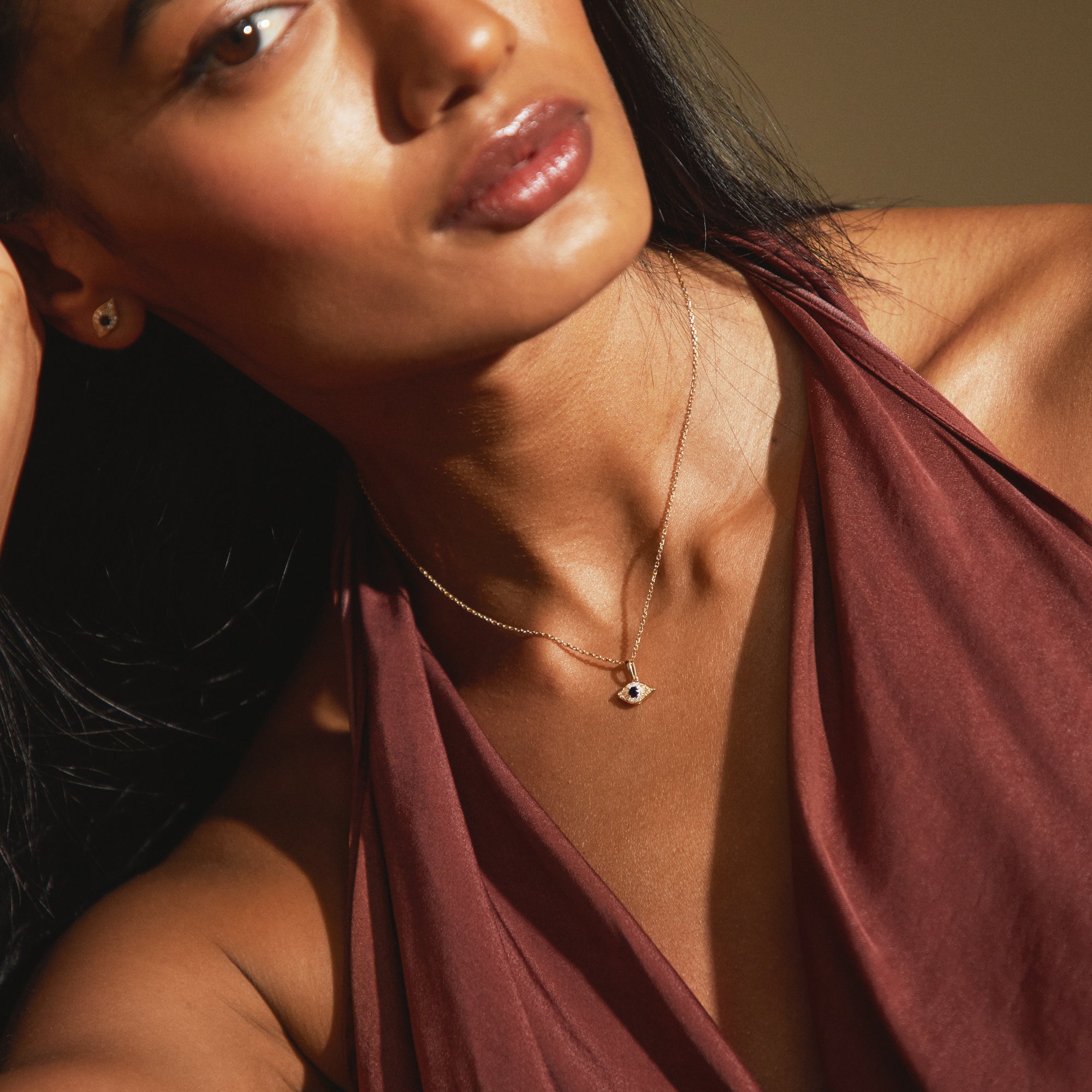 Model wearing the Modern Mangal Amina Necklace in 18K gold with an elegant sapphire evil eye pendant, resting naturally against the skin for everyday spiritual luxury and subtle elegance.