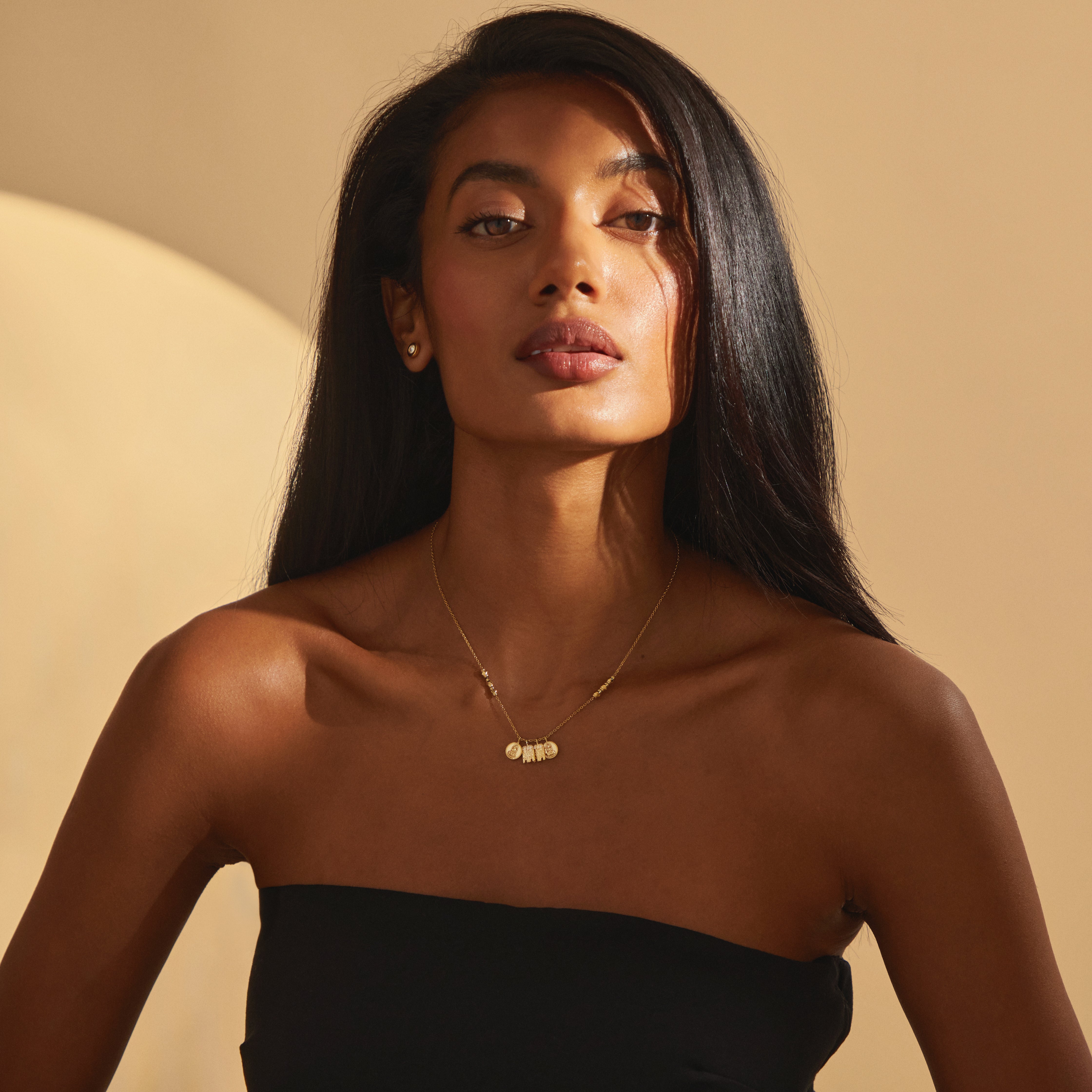 Wide shot portrait of a woman wearing the Madhura Mangalayam in yellow gold, a modern mangal necklace with tulsi-inspired and Lakshmi bottu pendants blending Tamil and Telugu traditions.
