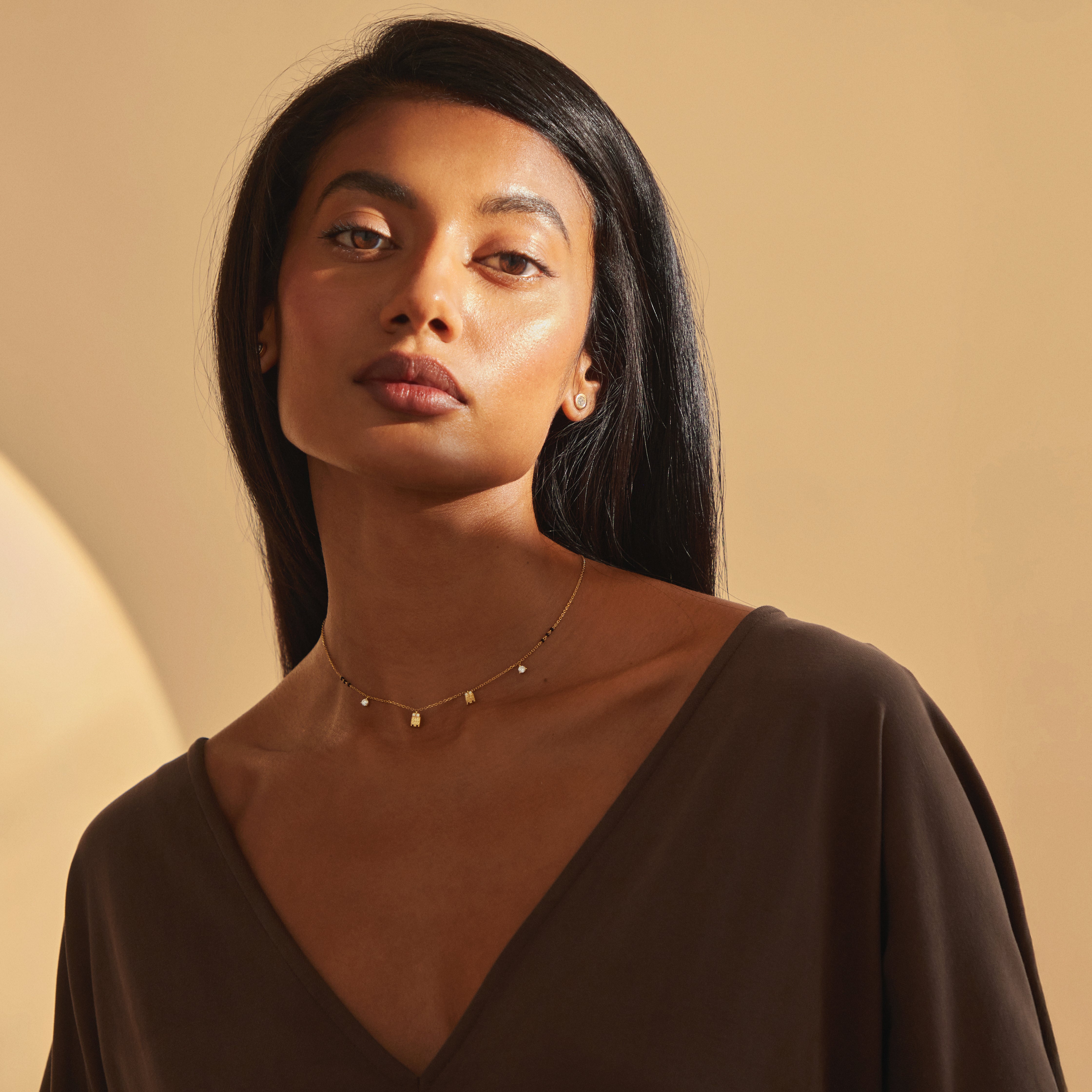 Wide-shot of model wearing the Meera Mangalayam by Modern Mangal, featuring a sacred tulsi pendant design with dangling lab diamonds, handcrafted in 18K solid yellow gold with bead accents along the Harmony Chain.