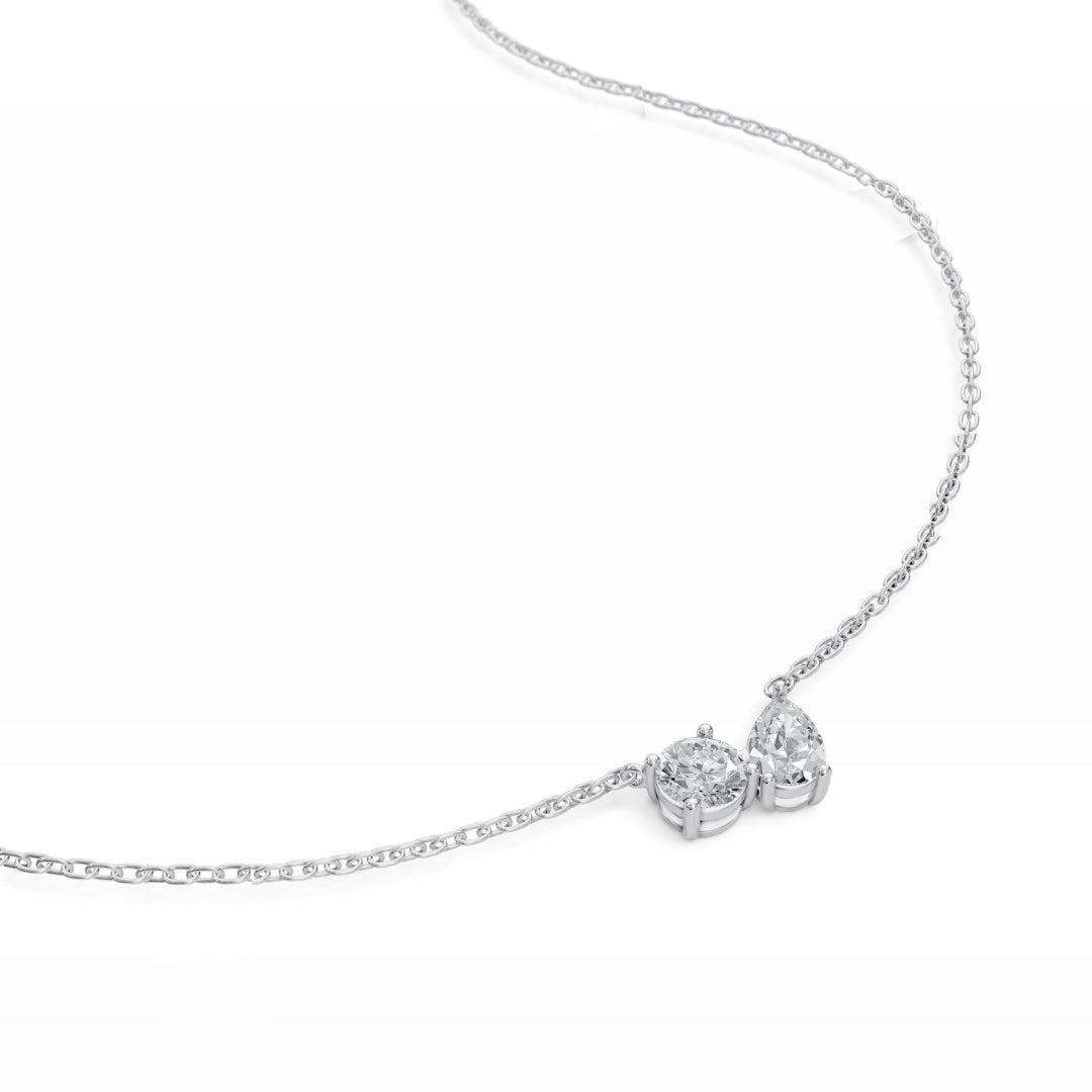 Detailed view of the white gold Modern Mangal Nina pendant, focusing on the asymmetrical elegance of the round and pear diamonds set side-by-side.