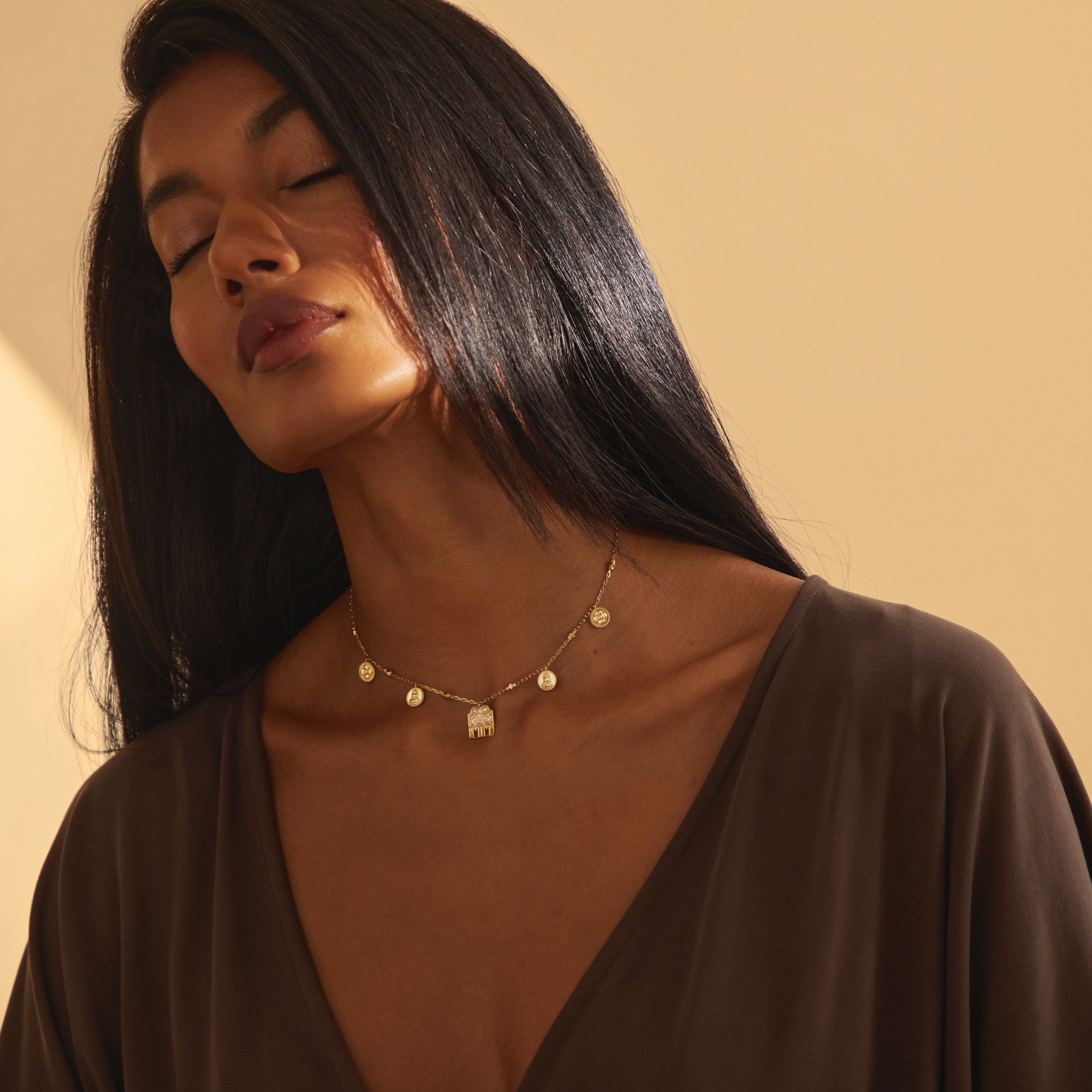 A serene moment showcasing the yellow gold Sravya Mangalayam necklace from Modern Mangal, highlighting its devotional Shivling charm flanked by floral and Lakshmi coin accents symbolizing matrimonial harmony.