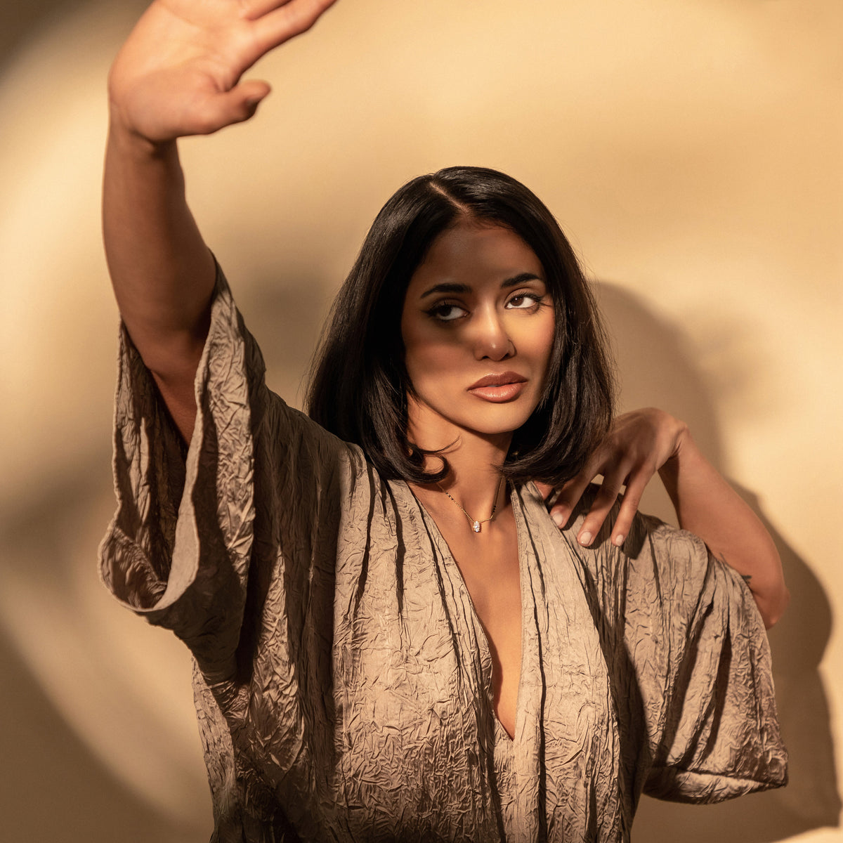 Model wearing the Suhani Mangalsutra in 18K gold with an oval diamond between grouped black beads, one arm raised