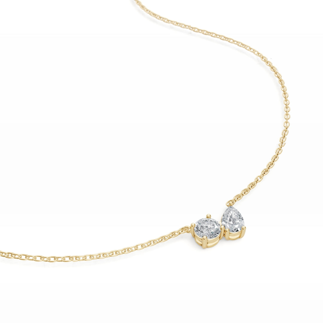  Close-up of the Modern Mangal nina pendant in yellow gold, with a brilliantly cut round and pear diamond placed in an elegant Toi et Moi layout.