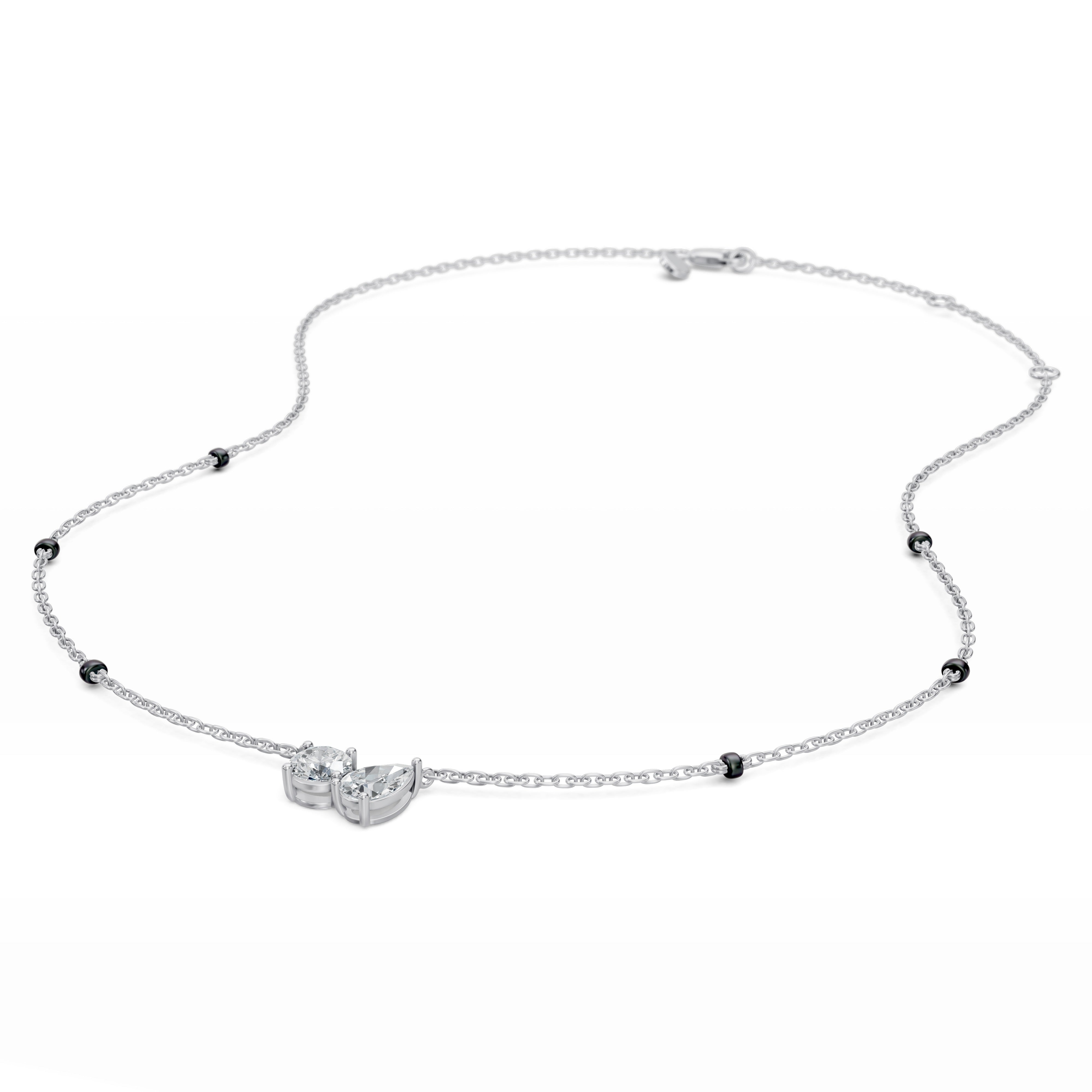 Close-up of the Modern mangal Toi et Moi pendant in white gold, showing the brilliance of the round diamond and the elegance of the pear diamond side by side.