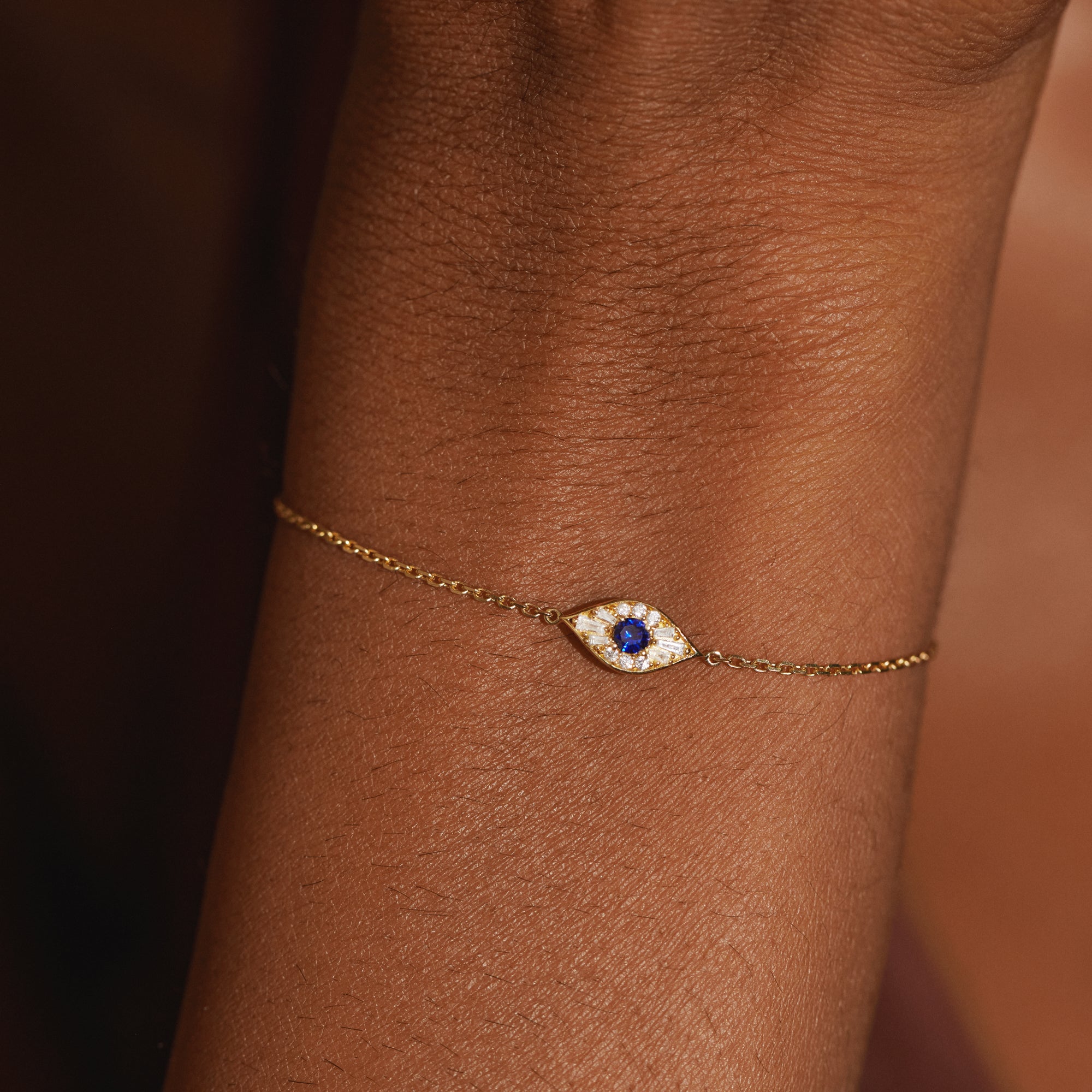 Close-up detail of the Modern Mangal Aira Bracelet on wrist, showcasing the central sapphire surrounded by baguette and round diamonds in a protective evil eye motif.