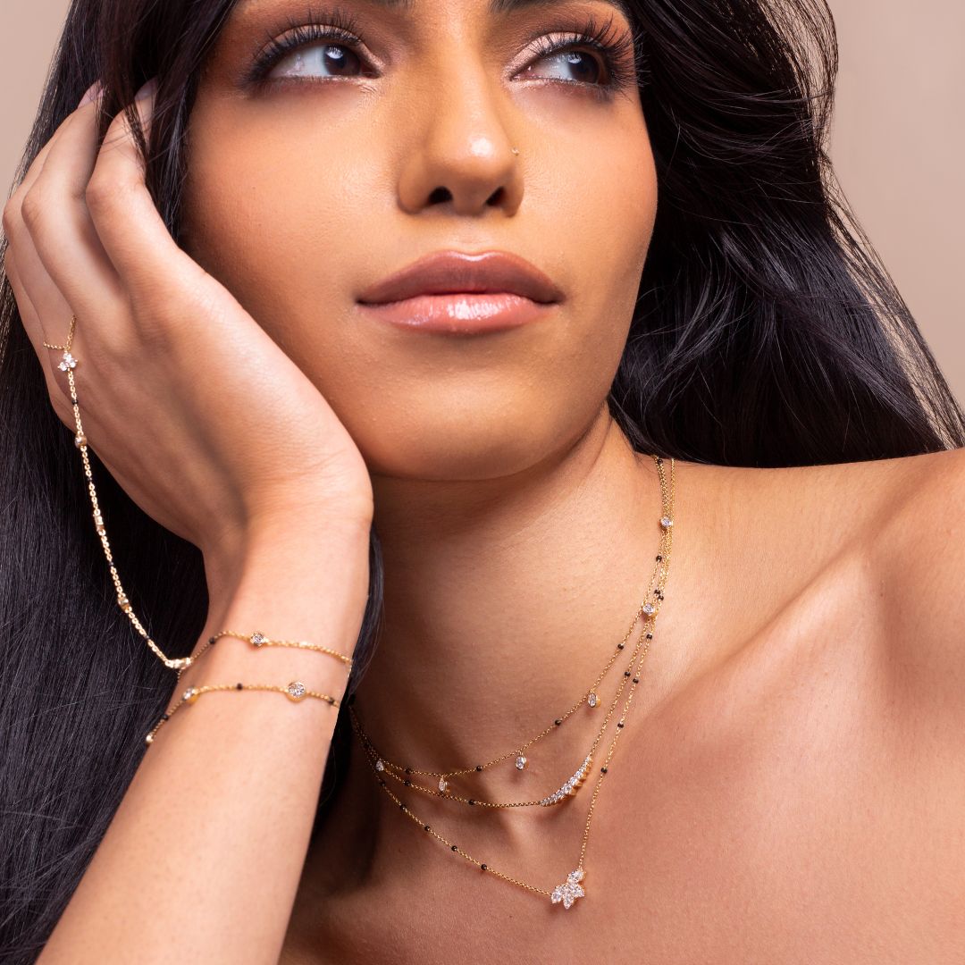 Model showcasing the intricate details of a necklace and bracelet set from the Modern Mangal x Ashna Gray Ashna Collection. The jewelry features delicate gold chains with black beads and diamonds, symbolizing a fusion of tradition and contemporary style.