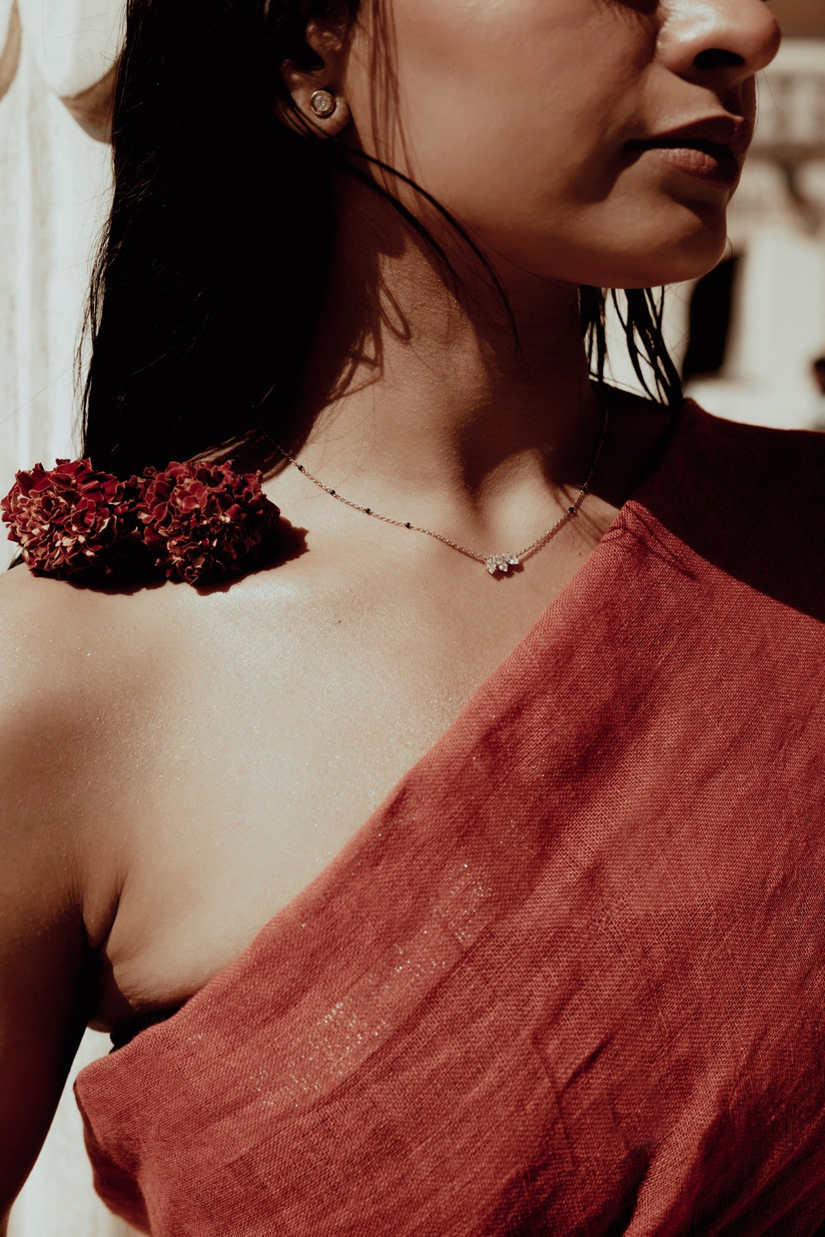 A beaded mangalsutra with a two-stone diamond pendant, worn with a red sari and marigolds