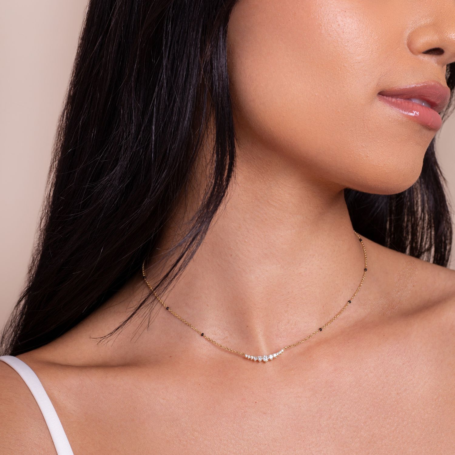 Close-up of the Harmony Necklace from the Modern Mangal x Ashna Gray Collection, showcasing a simple gold chain with diamond accents and black beads, perfect for layering.