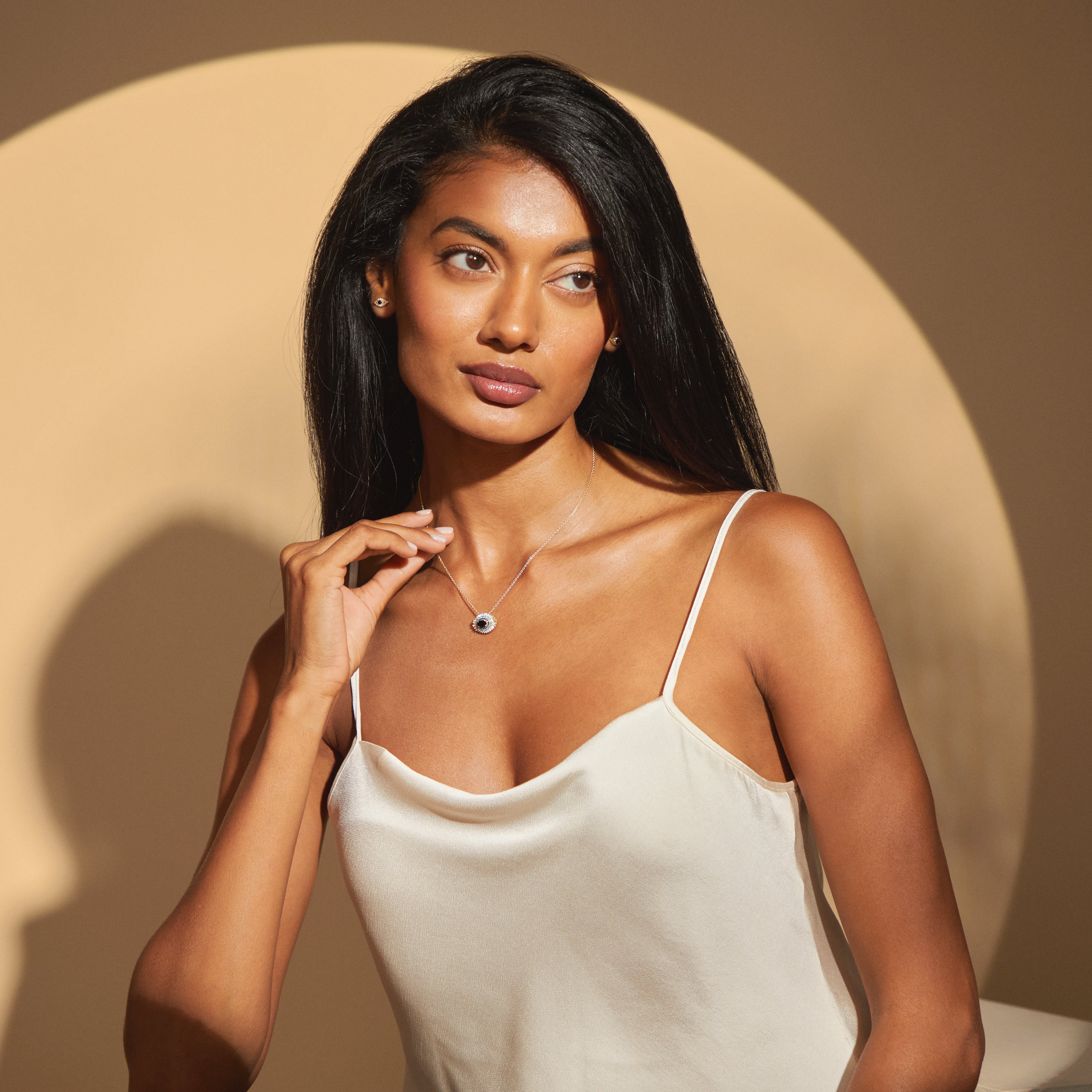 Wide shot of model wearing the Hira Necklace in yellow gold, highlighting the concentric circles of protection in the evil eye pendant against sunlit skin.