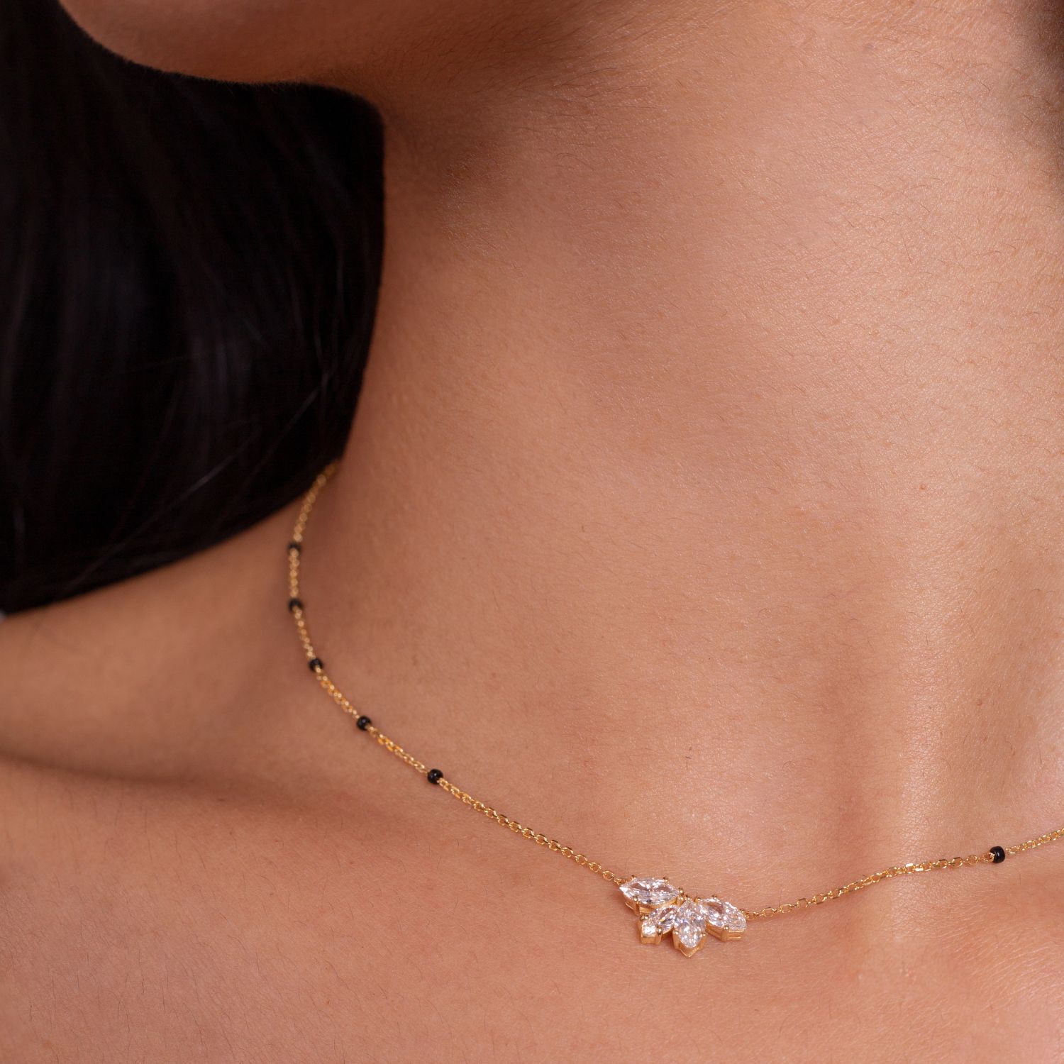 Close-up of the Love in Bloom Necklace from the Modern Mangal x Ashna Gray Collection, featuring a delicate floral diamond pendant on a gold chain with black bead accents.