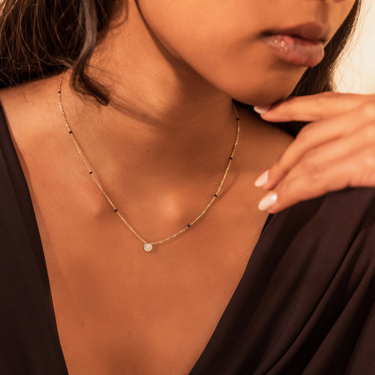 Close-up of the Minnie Mangalsutra in 18K gold on a model, with a bezel-set round diamond and black beads