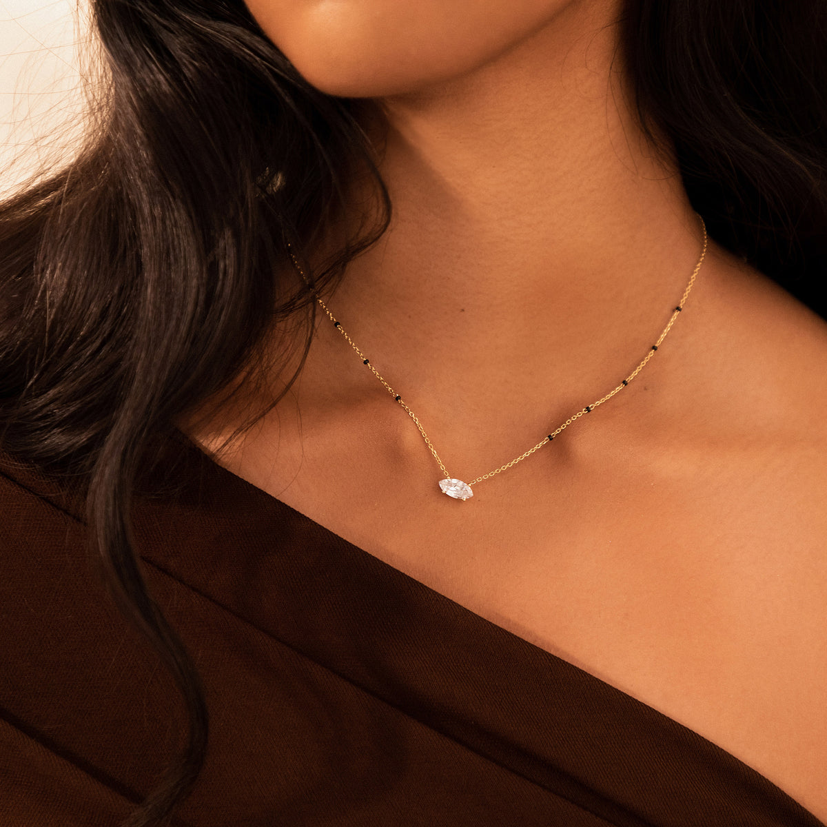Close-up of a model wearing the Myra Mangalsutra in 18K yellow gold, with an east-west marquise lab-grown diamond and spaced black beads
