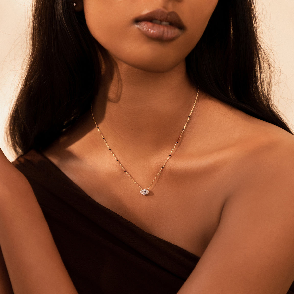 Model wearing the Myra Mangalsutra in 18K yellow gold and a one-shoulder top, with an east-west marquise lab-grown diamond between spaced black beads