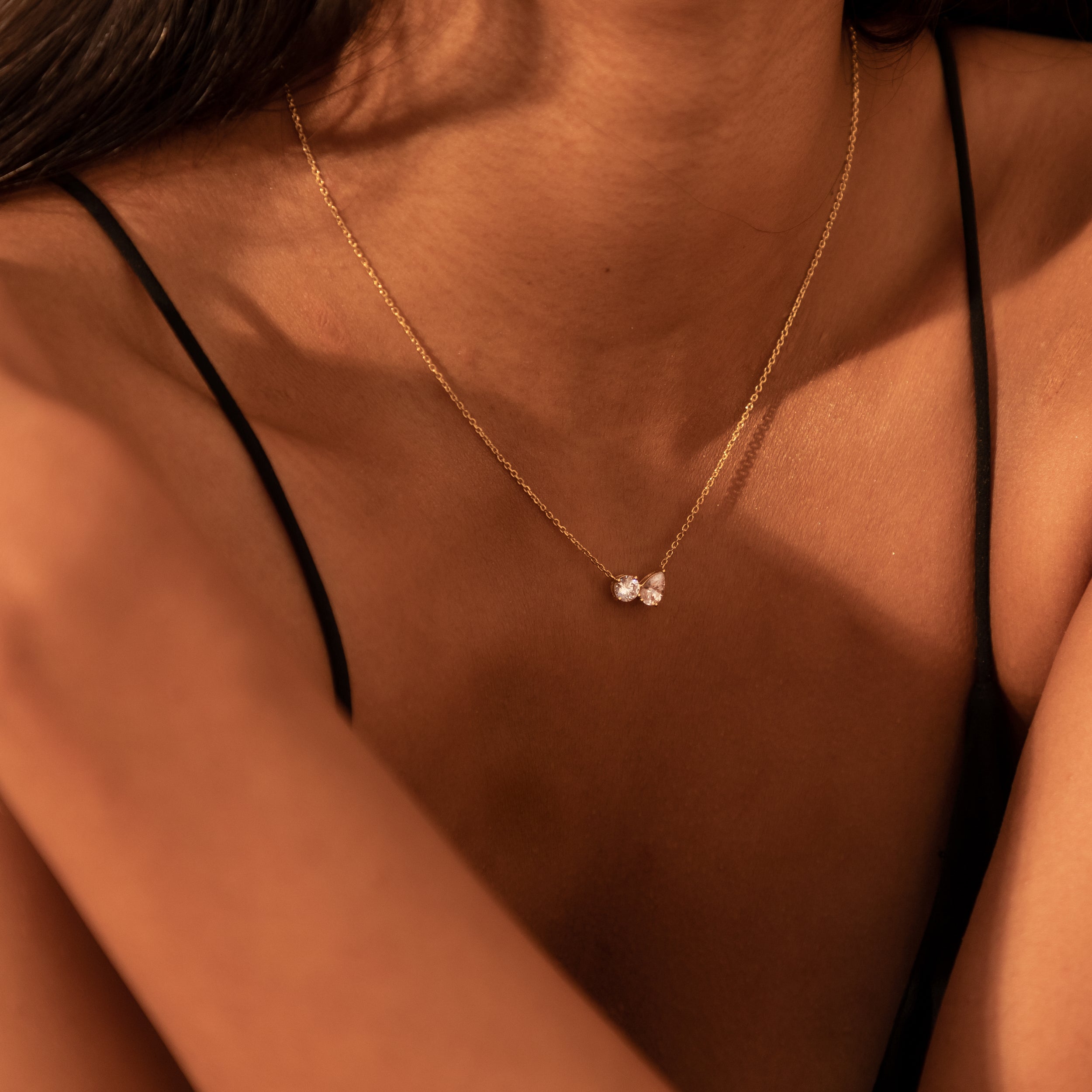  Close-up view of the Modern Mangal nina Necklace pendant, showcasing the brilliance and contrast between the round and pear-shaped diamonds set on a delicate yellow gold chain.