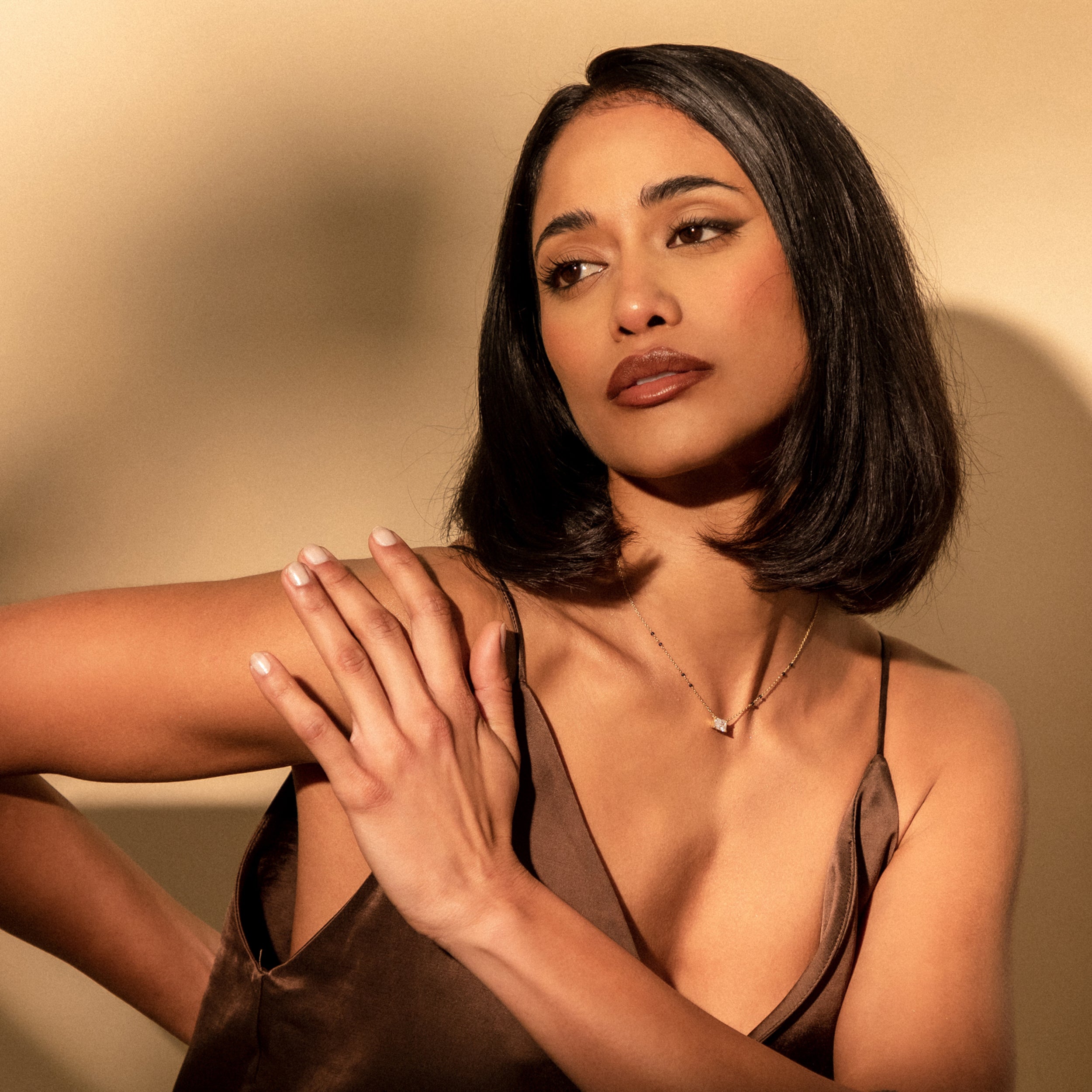 Pensive, angled view of model wearing the Modern Mangal Radhi Mangalsutra, illustrating the graceful fall of the pendant against a deep neckline.