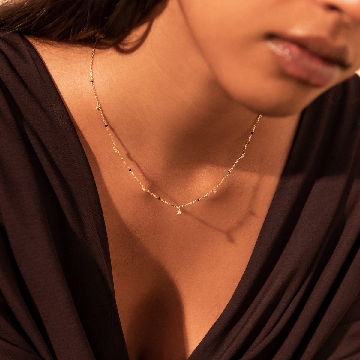 Close-up of the Tara Mangalsutra in 18K gold on a model's neckline, with scattered diamonds among black beads
