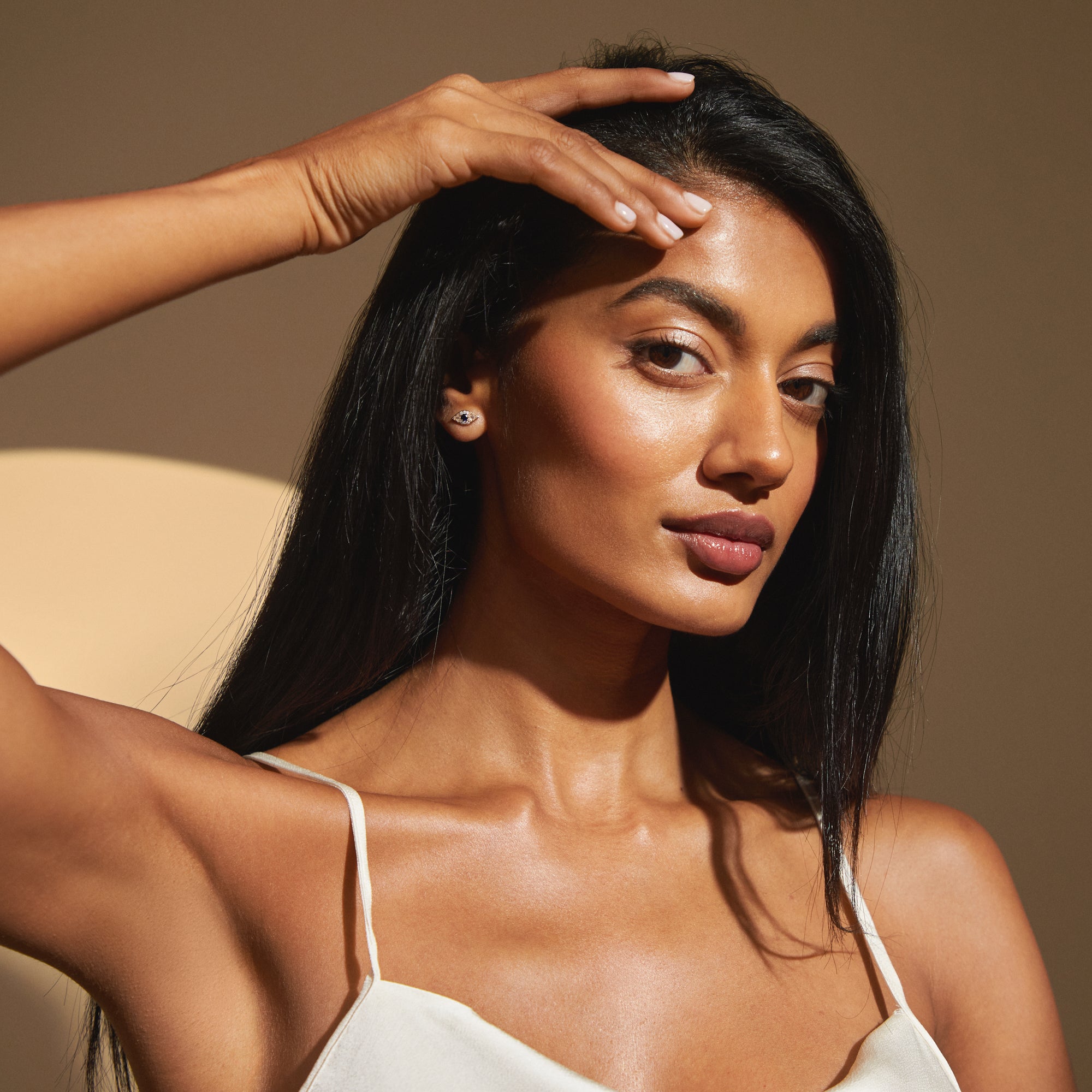 Portrait of model wearing Modern Mangal Zuri Studs in yellow gold with subtle, natural lighting emphasizing the symmetrical sparkle and protective elegance of the earrings.

