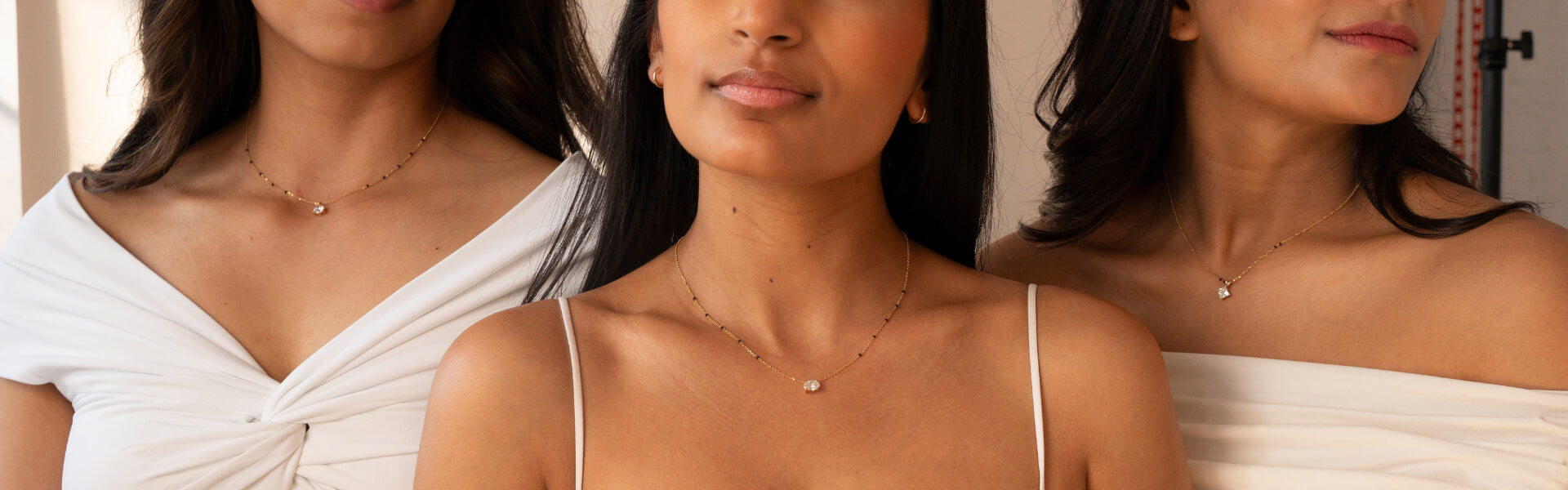 Three women wearing elegant gold and diamond Mangalsutra necklaces, highlighting a modern and minimalistic jewelry style.